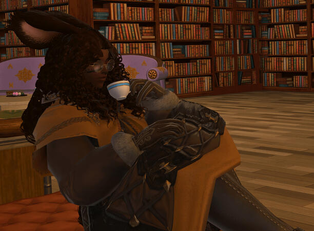 Emery, a viera, is sitting on a lounge cushion in a library. They are about to drink a cup of tea. She is wearing a brown and yellow padded tunic, fur lined gloves, and leather thigh boots. They appear content.