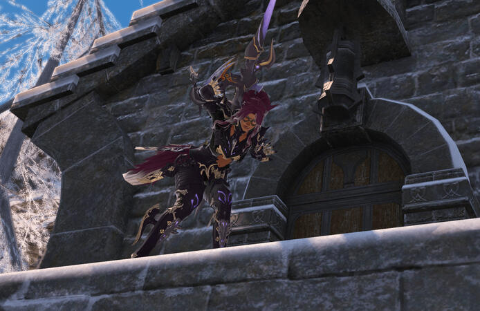 Lili'a, is wearing the dragoon job armor. She is standing on the ledge of one of the buildings at the Observatorium in Coerthas. He is looking down at the camera and waving happily.